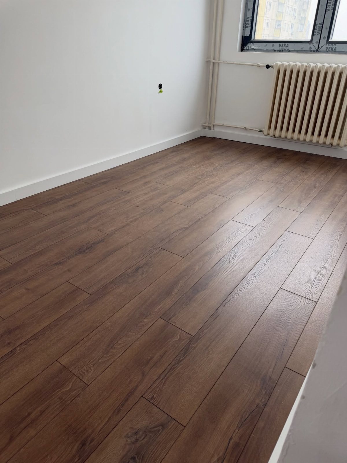 Dark brown wood-look flooring planks installed in an empty room with white walls.