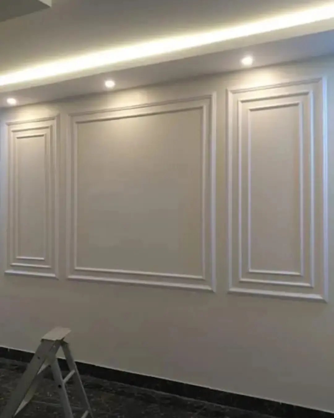 Three rectangular picture frame moldings installed on a light-colored interior wall under ceiling lighting.
