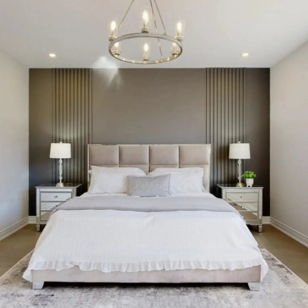 A modern bedroom with a dark grey accent wall featuring vertical wood slats behind a beige bed.