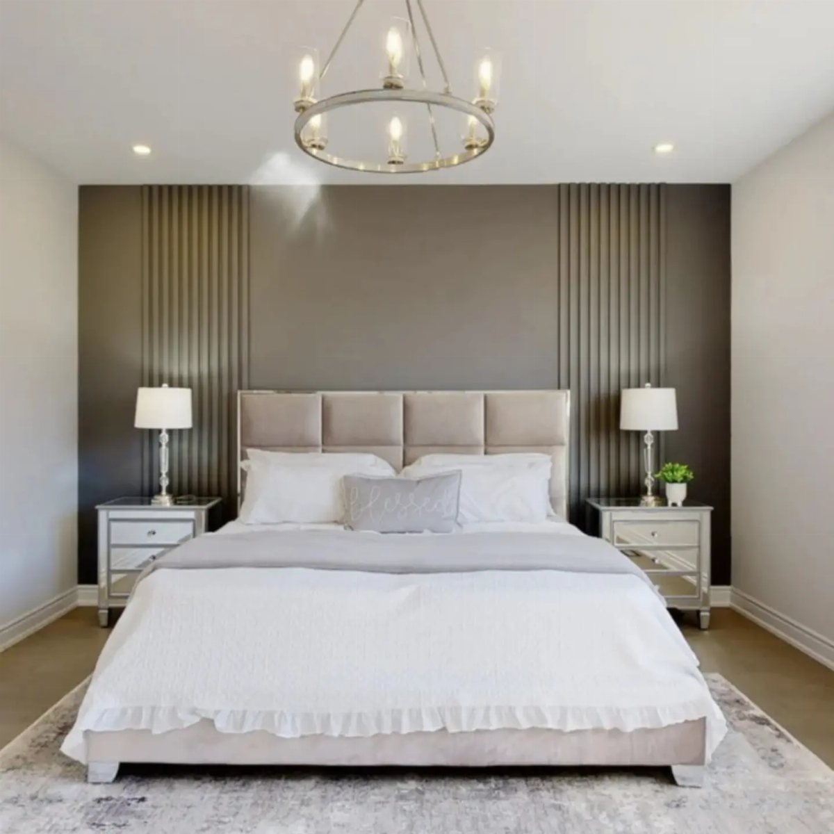 A modern bedroom with a dark grey accent wall featuring vertical wood slats behind a beige bed.